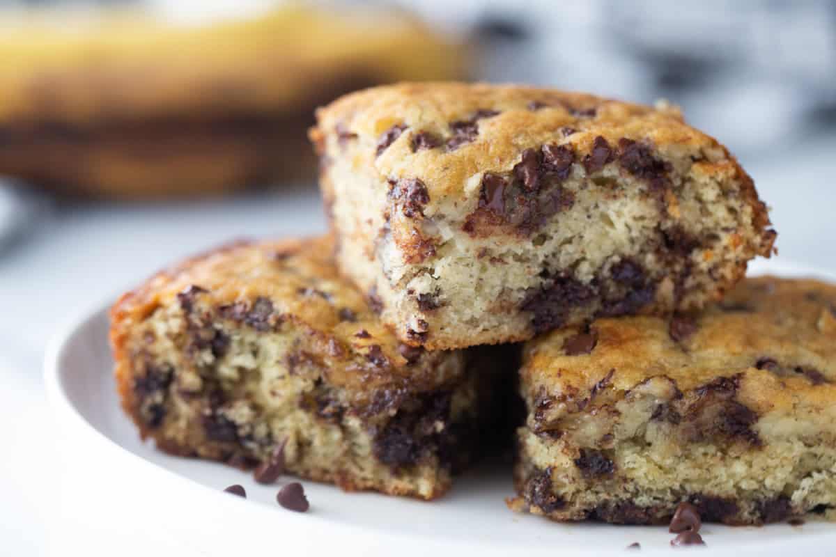 Chocolate chip banana snack cake that’s soft, moist and easy to make. A simple one-pan dessert everyone will love! stacked pieces of chocolate chip banana snack cake