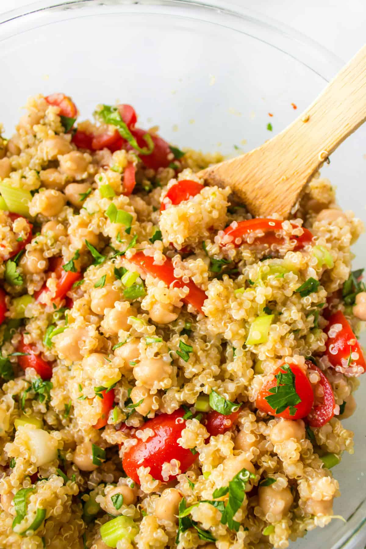 Easy quinoa salad with chickpeas, tomatoes and a lemon dressing. Fresh, healthy and perfect for meal prep or a quick meal! stirring quinoa salad in bowl