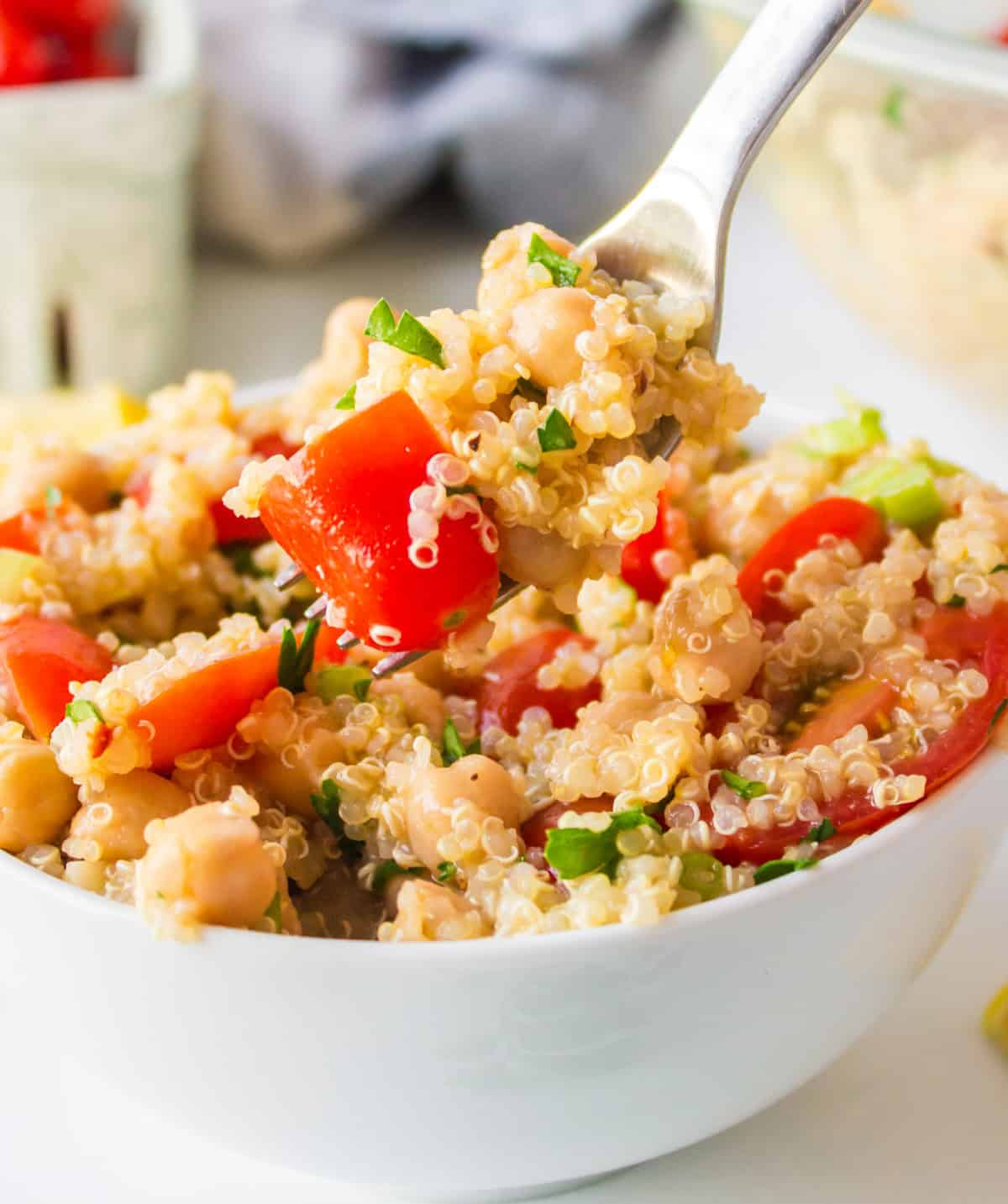 Easy quinoa salad with chickpeas, tomatoes and a lemon dressing. Fresh, healthy and perfect for meal prep or a quick meal! spooning out quinoa salad from bowl