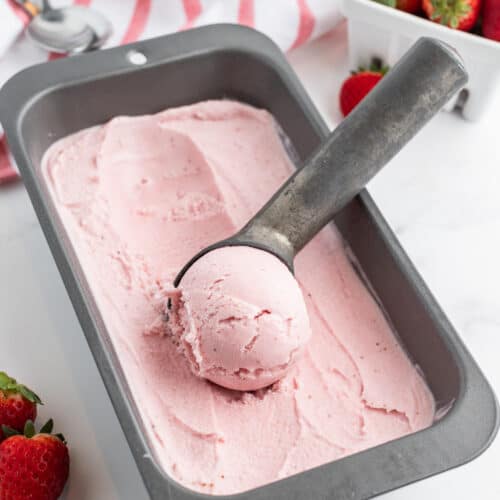 pan of homemade strawberry ice cream with ice cream scoop in it