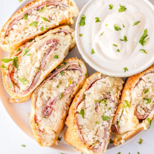 slices of chicken cordon bleu stromboli on plate with bowl of dipping sauce