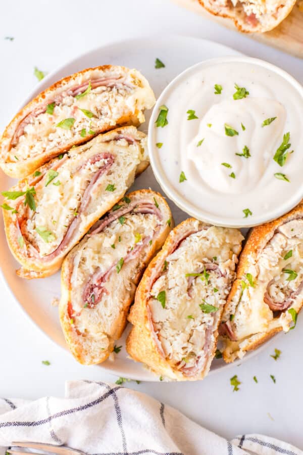 slices of chicken cordon bleu stromboli on plate with bowl of dipping sauce