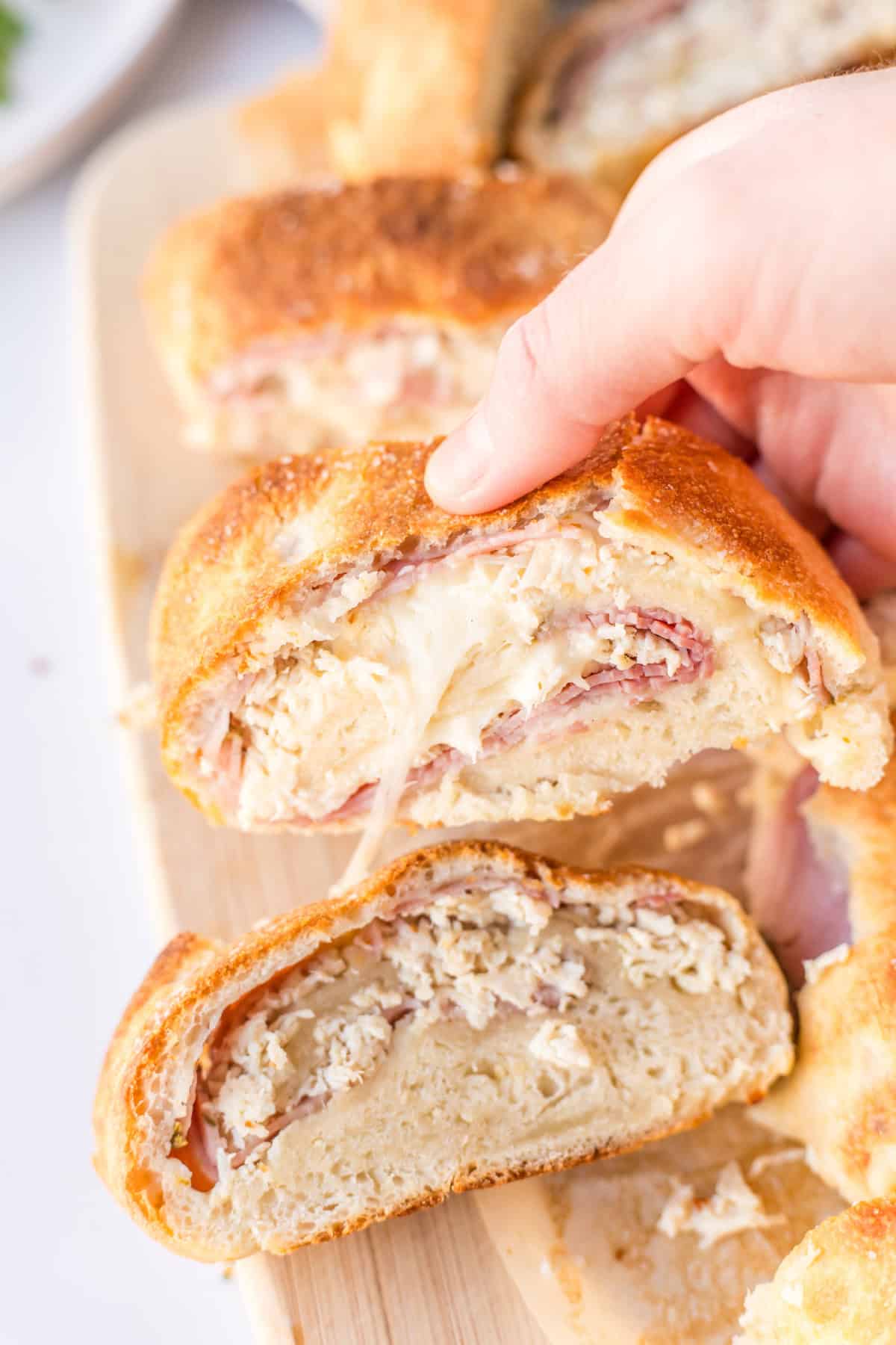 hand holding slice of chicken cordon bleu stromboli