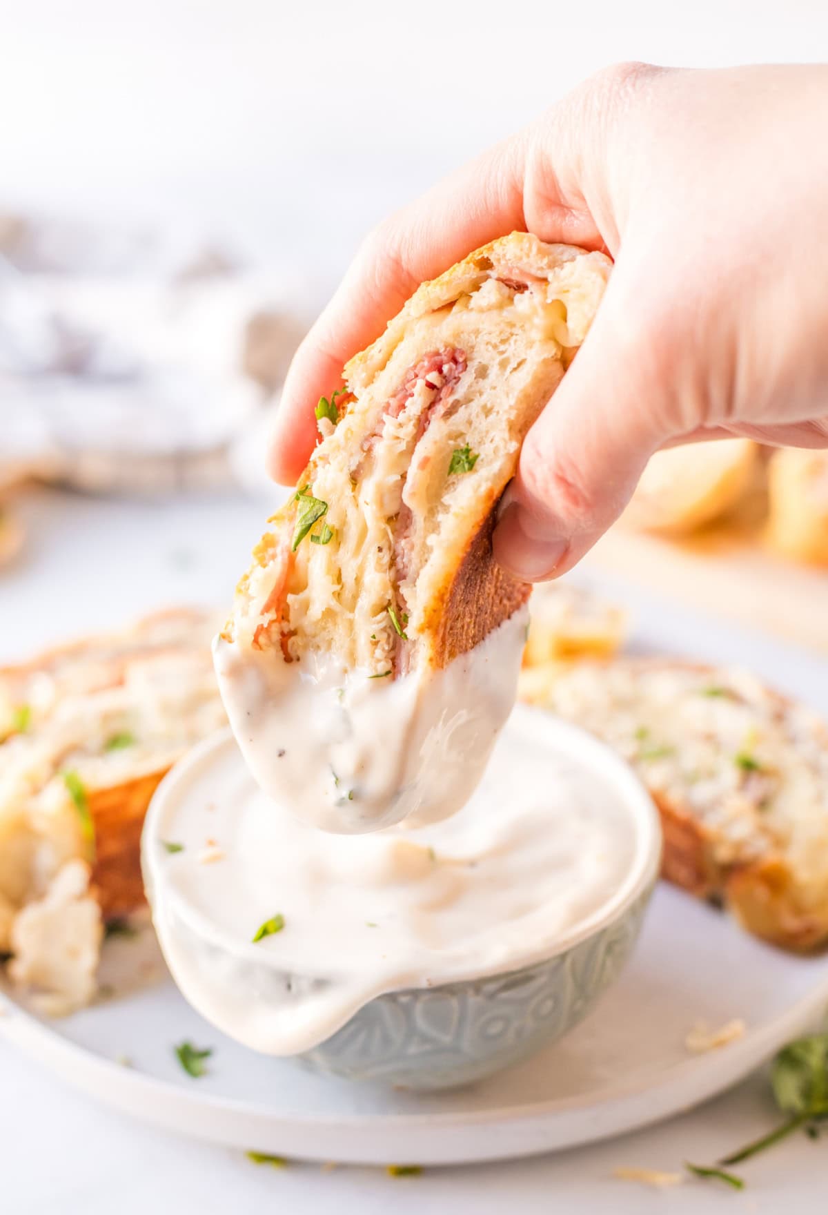 dipping chicken cordon bleu stromboli into sauce