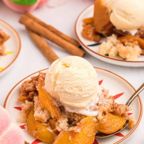 peach cobbler in a dish topped with vanilla ice cream