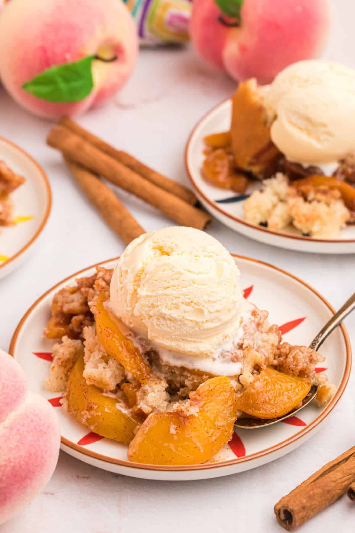 This Easy Peach Cobbler is packed with sweet peaches, warm cinnamon and nutmeg, and a buttery golden topping that tastes amazing with vanilla ice cream. Made with fresh or frozen peaches, it's the perfect summer dessert recipe for family gatherings, potlucks and holidays. Save this homemade peach cobbler recipe for later! #peachcobbler #peachdessert #summerdesserts #bakingrecipes #comfortfood peach cobbler in a dish topped with vanilla ice cream