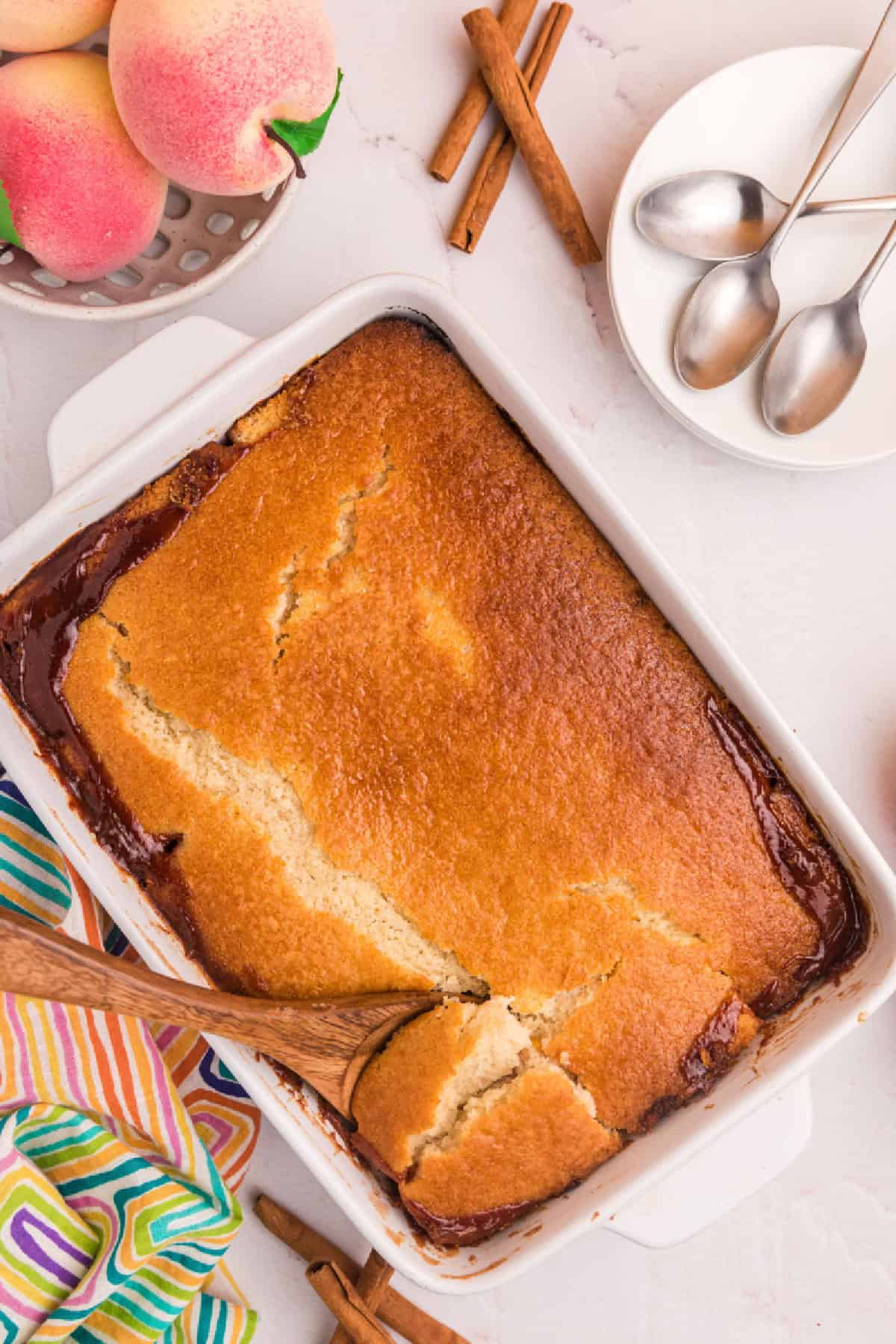 This Easy Peach Cobbler is packed with sweet peaches, warm cinnamon and nutmeg, and a buttery golden topping that tastes amazing with vanilla ice cream. Made with fresh or frozen peaches, it's the perfect summer dessert recipe for family gatherings, potlucks and holidays. Save this homemade peach cobbler recipe for later! #peachcobbler #peachdessert #summerdesserts #bakingrecipes #comfortfood peach cobbler in pan
