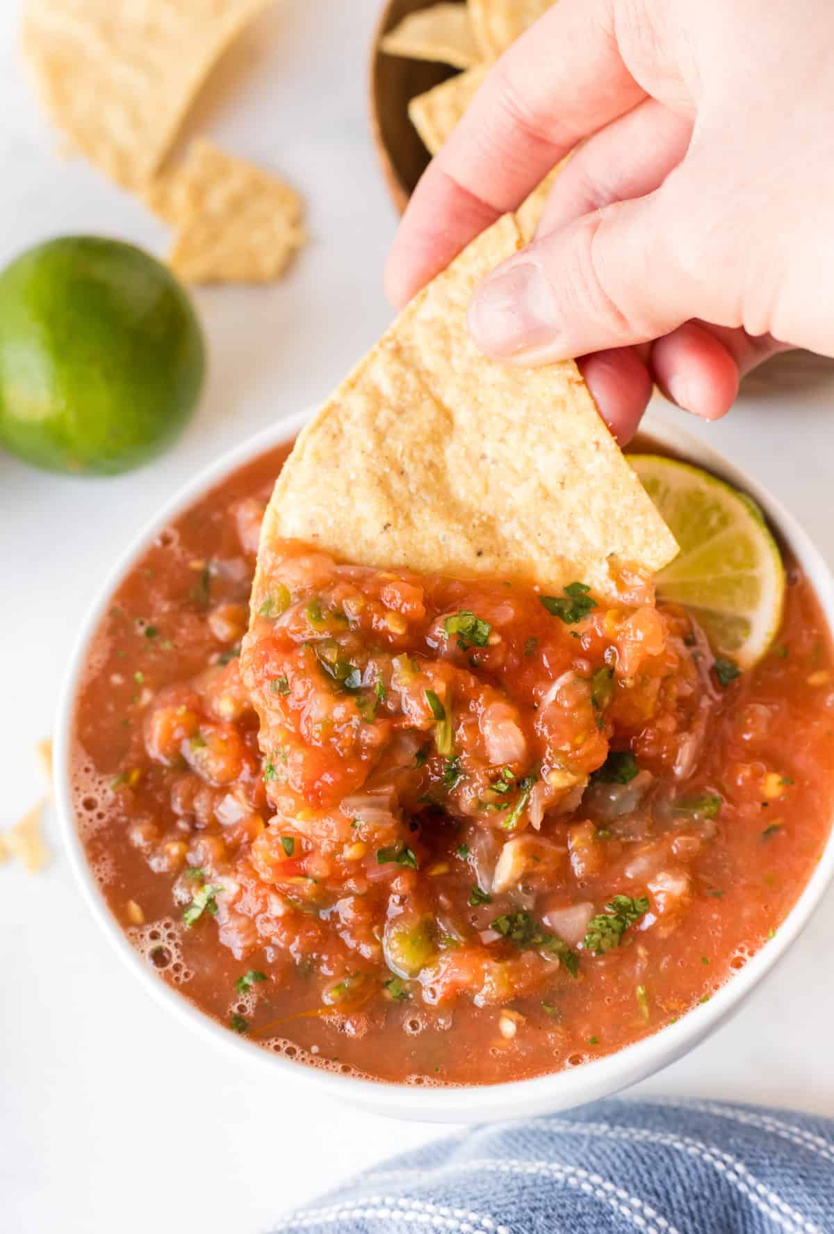 handing dipping chip into bowl of restaurant style salsa